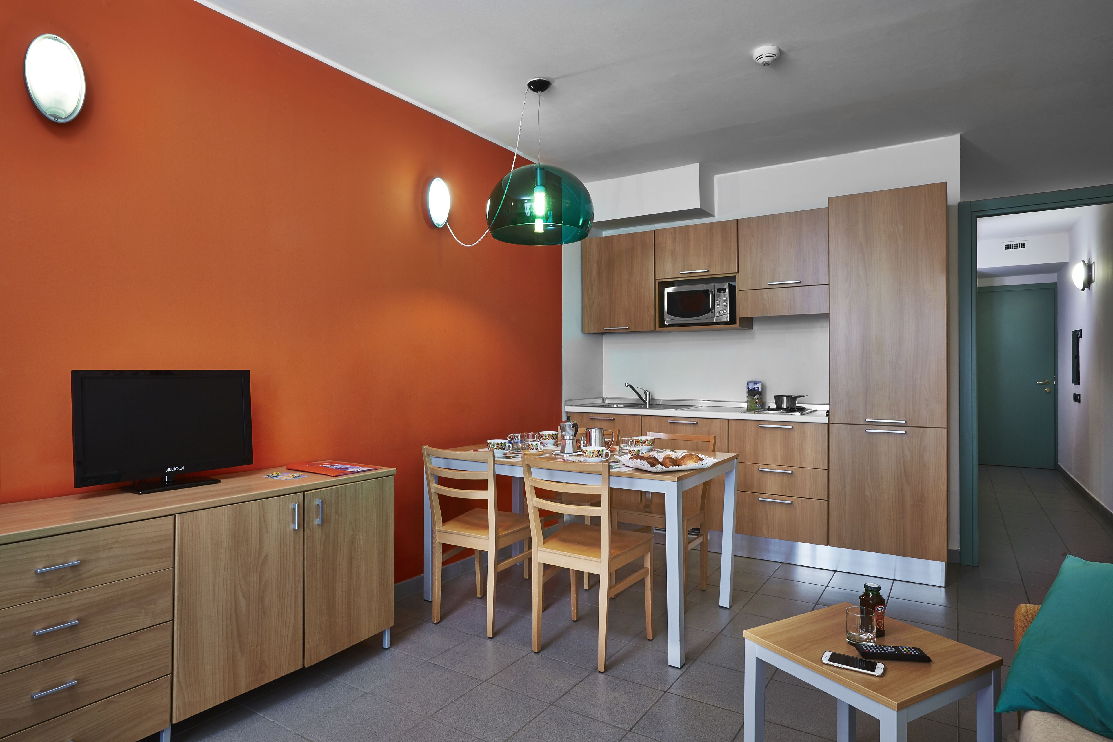 A modern kitchen with wooden cabinets, a dining table, and a TV.