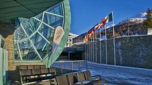 Un edificio moderno con un'ampia vetrata, una panchina e una bandiera.