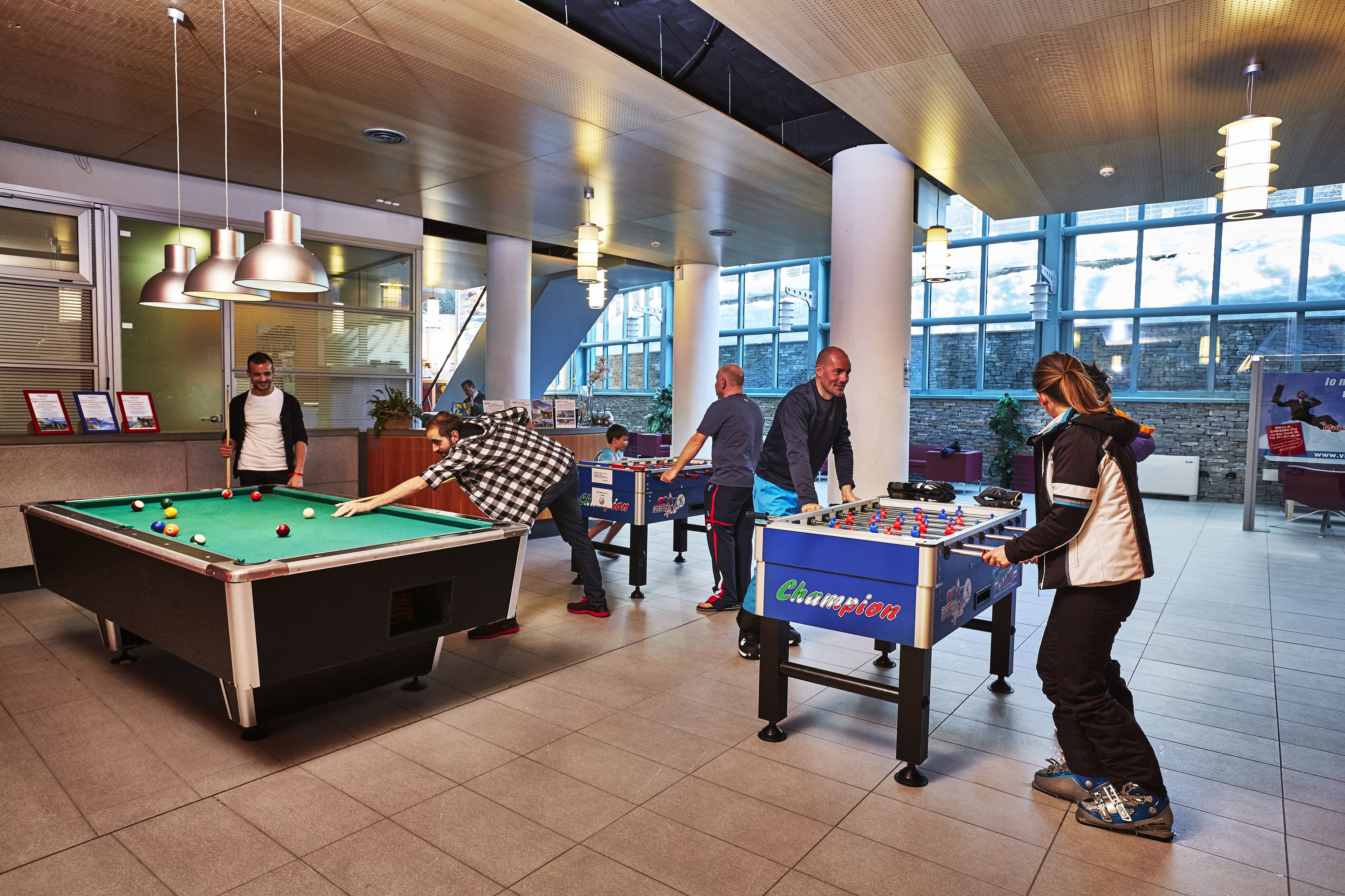Une table de billard et une table de baby-foot dans un espace intérieur bien éclairé, doté de grandes fenêtres.