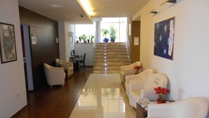 A hotel lobby with a reception desk, seating area, staircase, and potted plants. - Villa Rosetta (Umag)