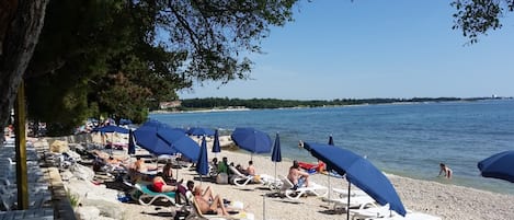 Una playa cerca, sillas reclinables de playa, sombrillas