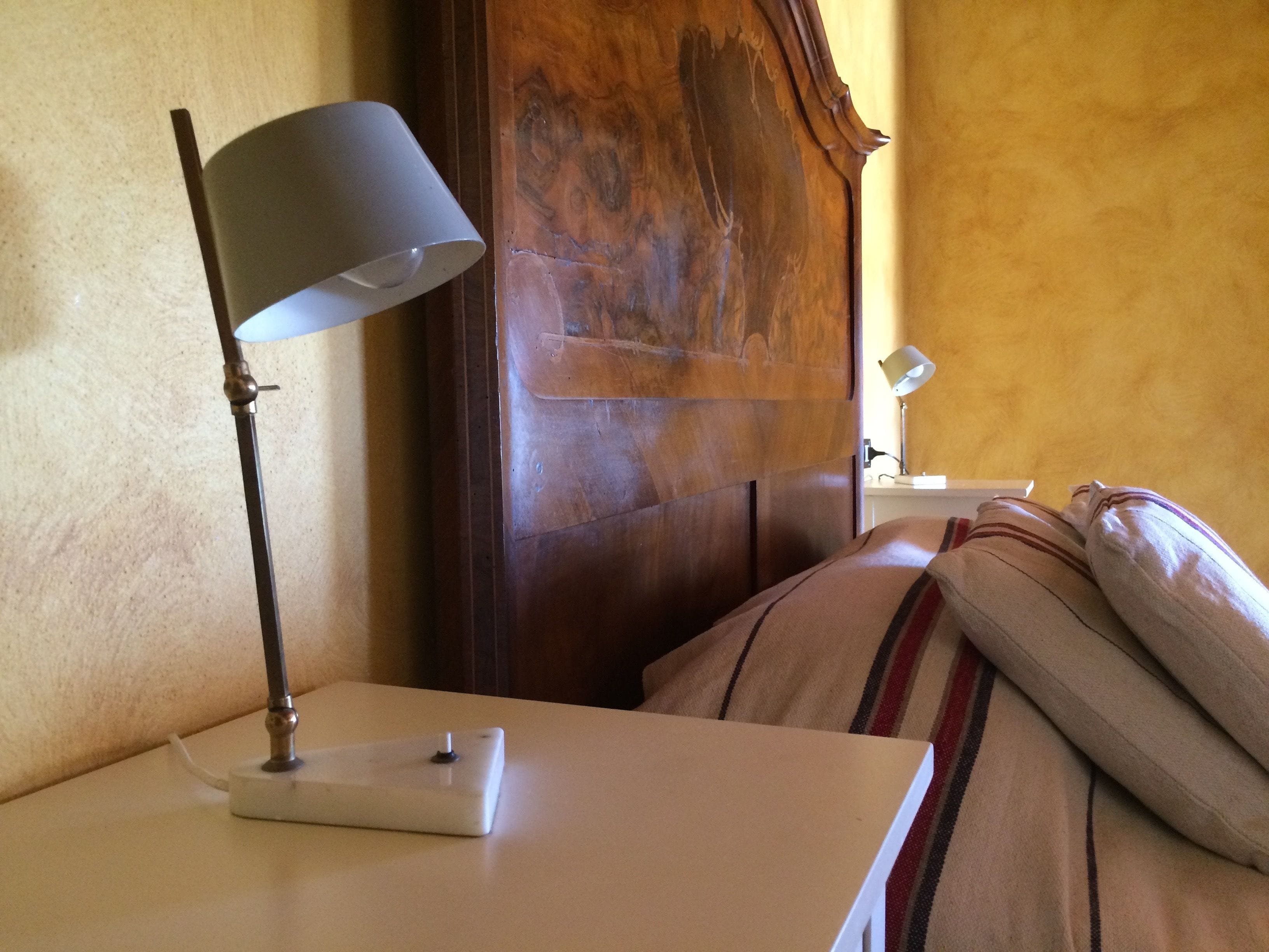 A bed with a striped pillow and a bedside table with a lamp.