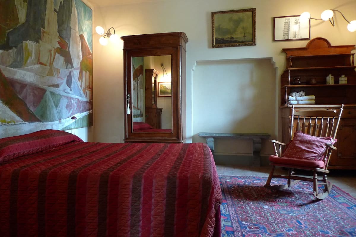 A room with a bed, a chair, a mirror, and a bookshelf.
