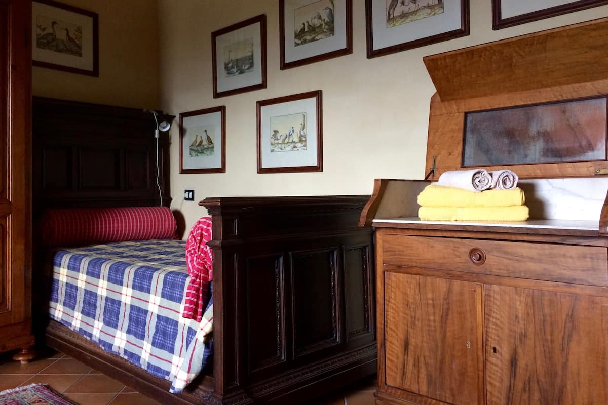 A bedroom with a bed, a wooden dresser, and a nightstand.