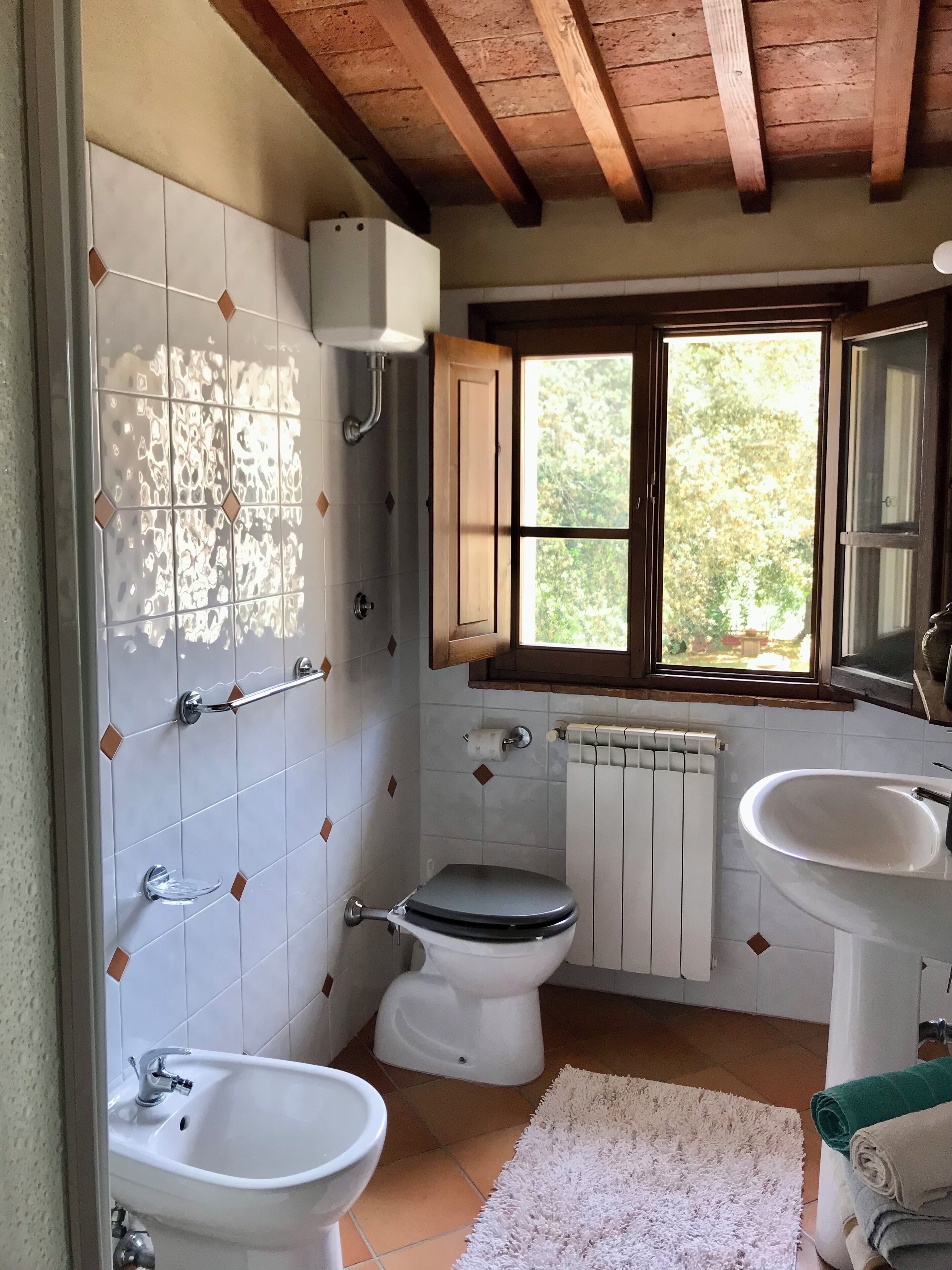 Un baño con inodoro, bidé, lavabo y ventana.