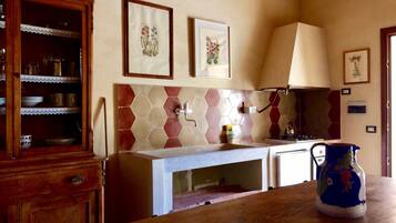 Una cocina con un mueble de madera, salpicadero de azulejos y una jarra azul sobre la encimera.
