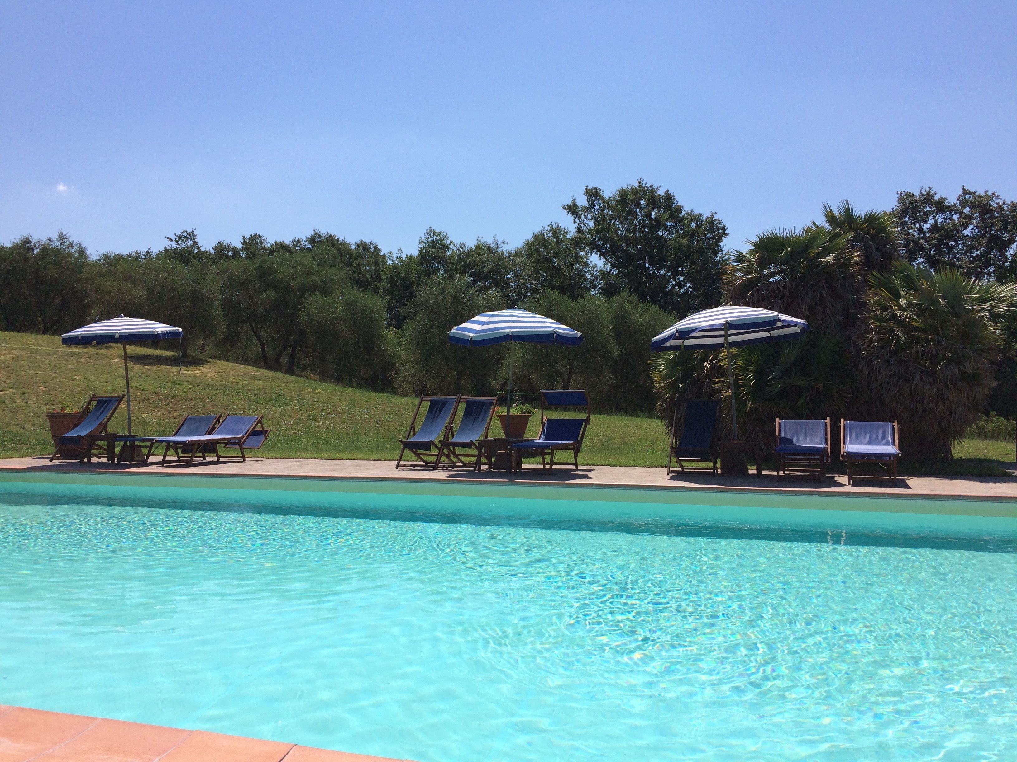A swimming pool with lounge chairs and striped umbrellas.