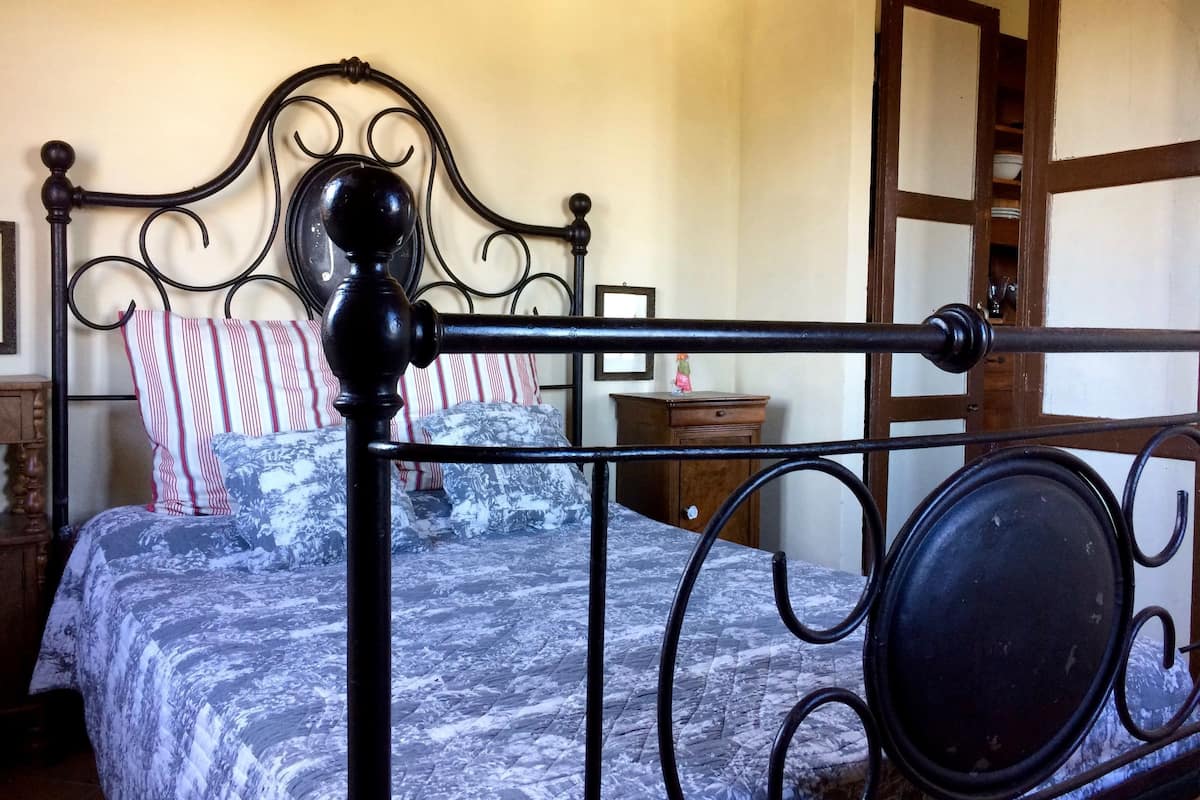 A bed with a metal frame and a headboard, a wooden nightstand, and a dresser with a mirror.