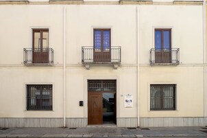 A building with three balconies, a central door, and barred windows.