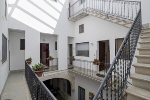 A multi-level interior with a central staircase, potted plants, and a tiled floor.