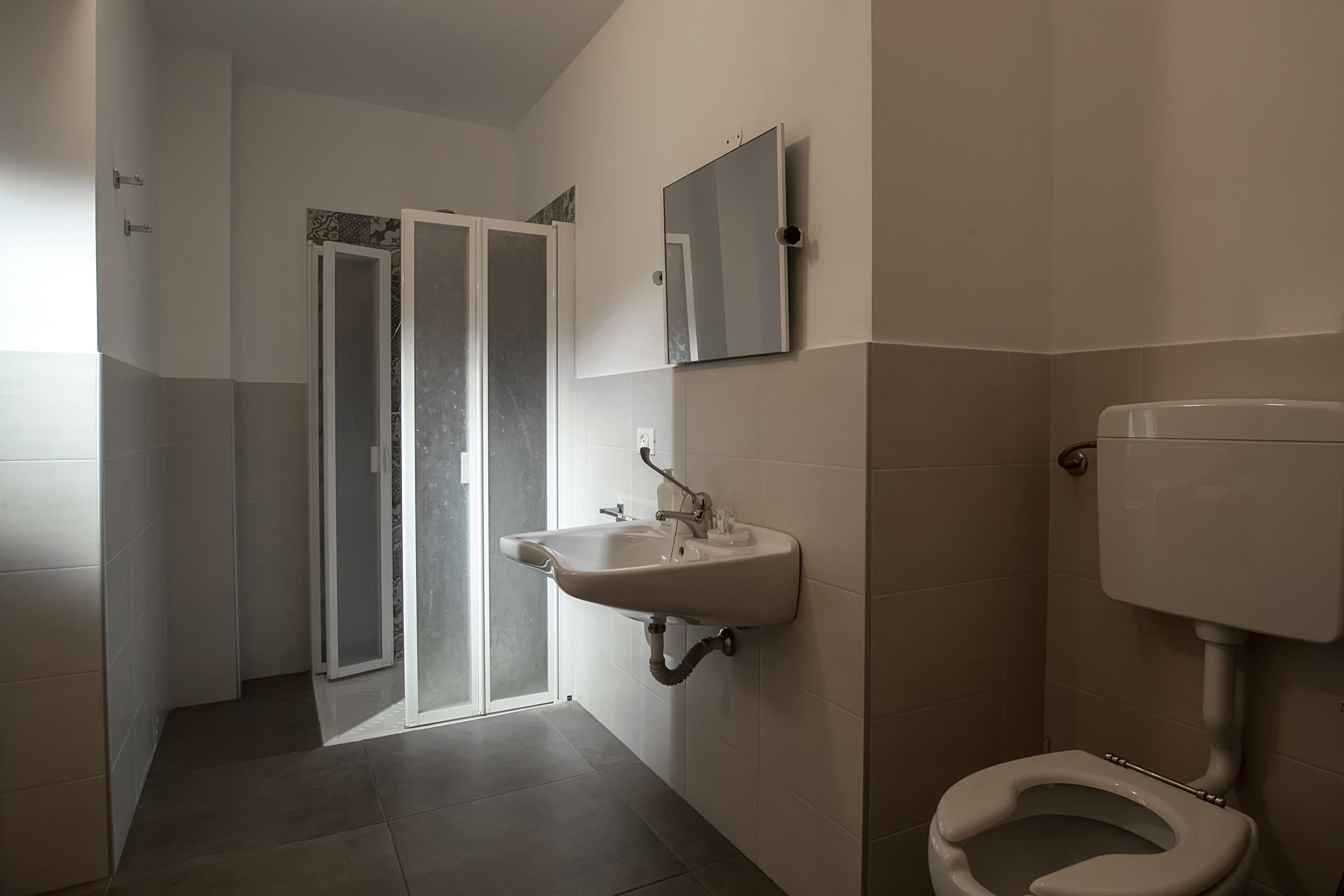 A bathroom with a toilet, sink, and a glass door leading to a shower area.