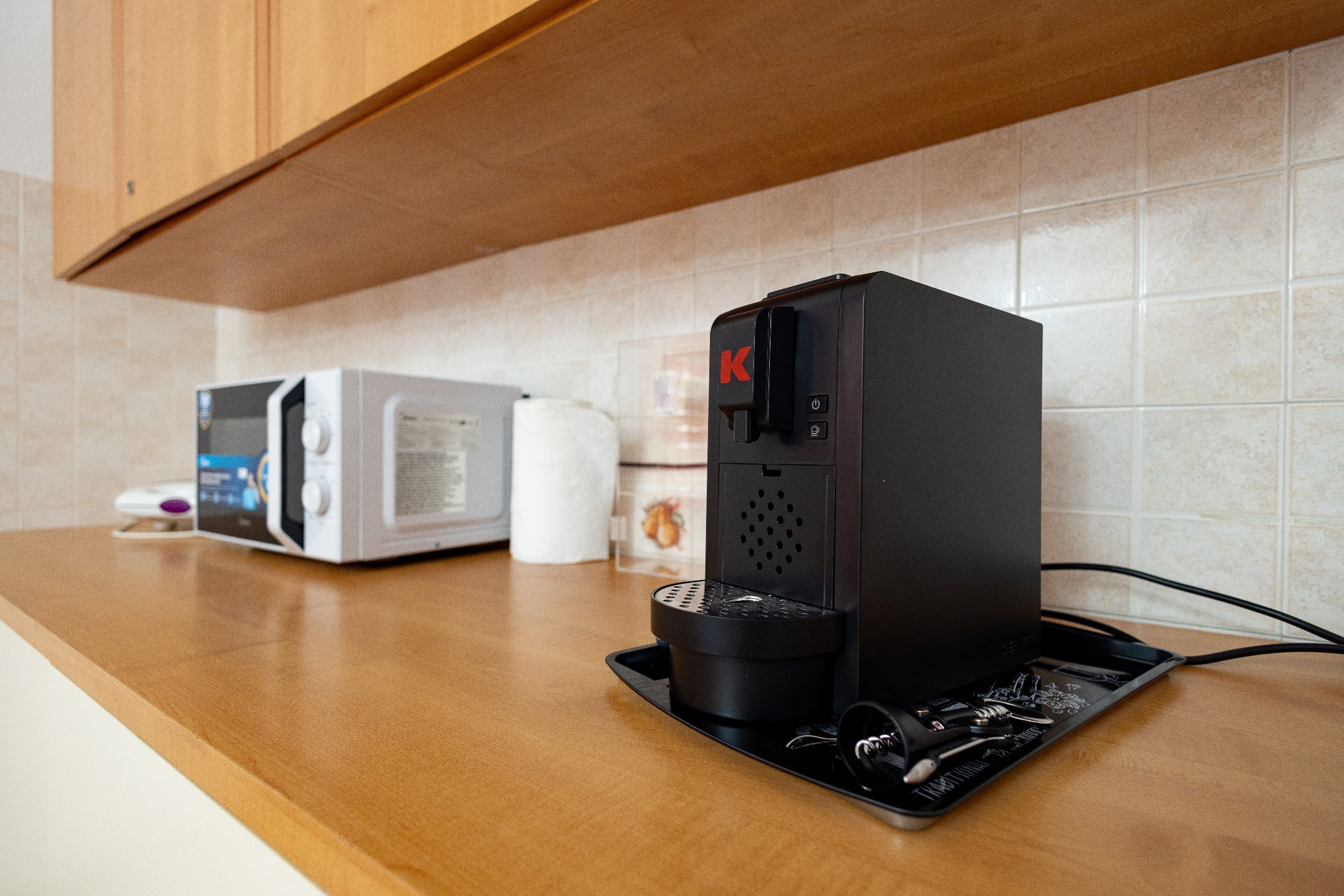 A kitchen with a coffee machine, microwave, and a toaster on the counter.