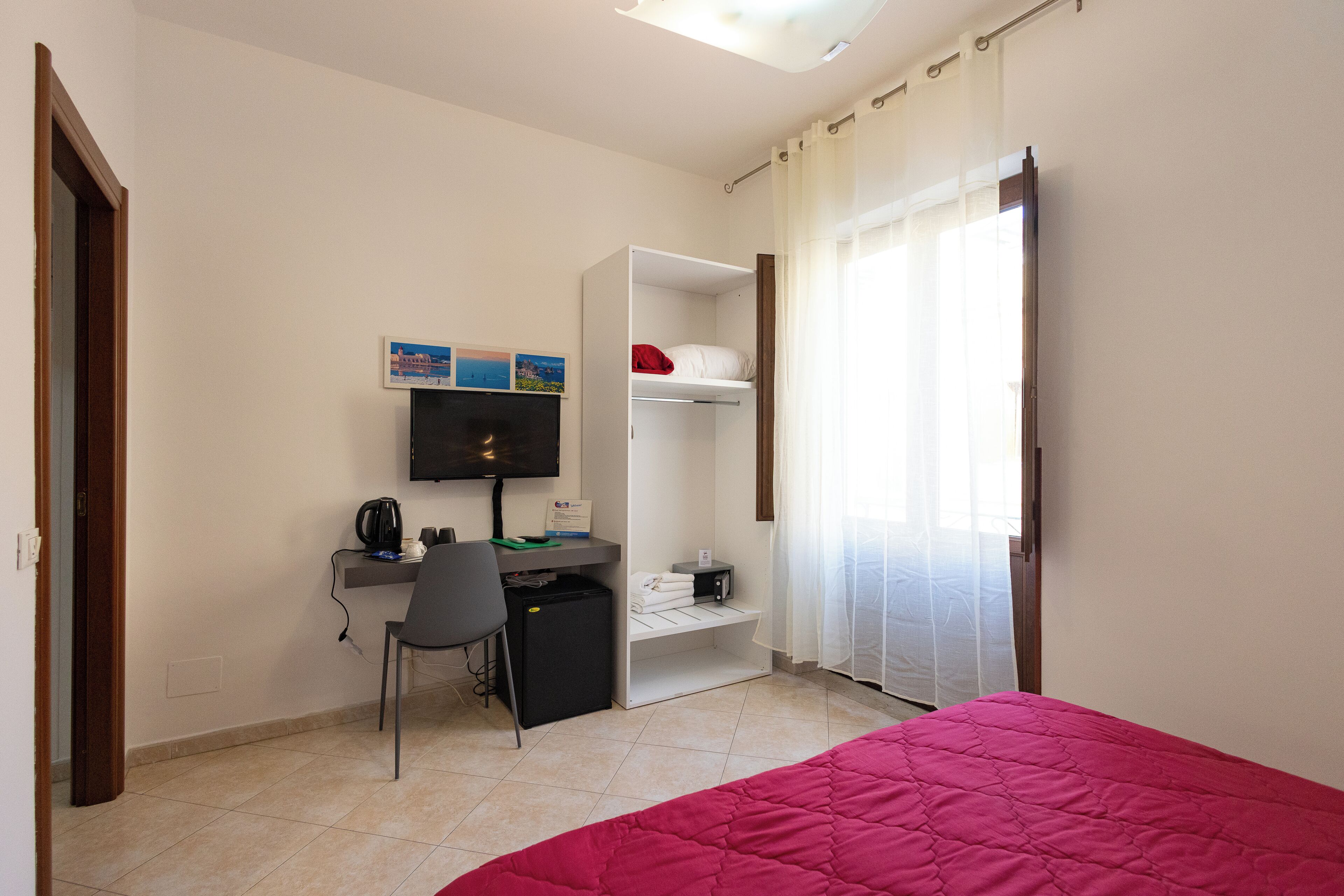 Une chambre à coucher comprenant un lit, un bureau, une chaise, une télévision et une armoire.