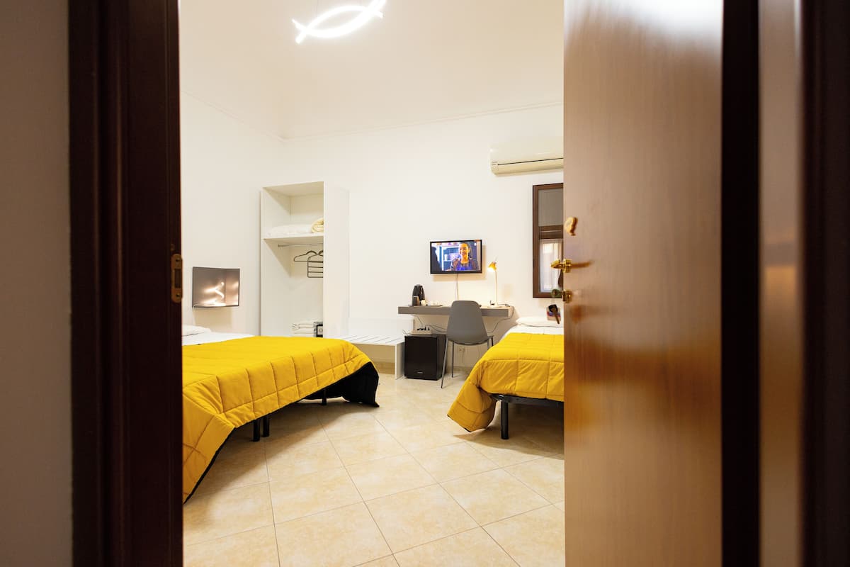 Una habitación de hotel con dos camas, un escritorio, una silla y un televisor.