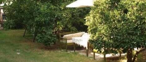 Un jardín con una estructura de techo de paja, rodeado de abundante follaje verde.