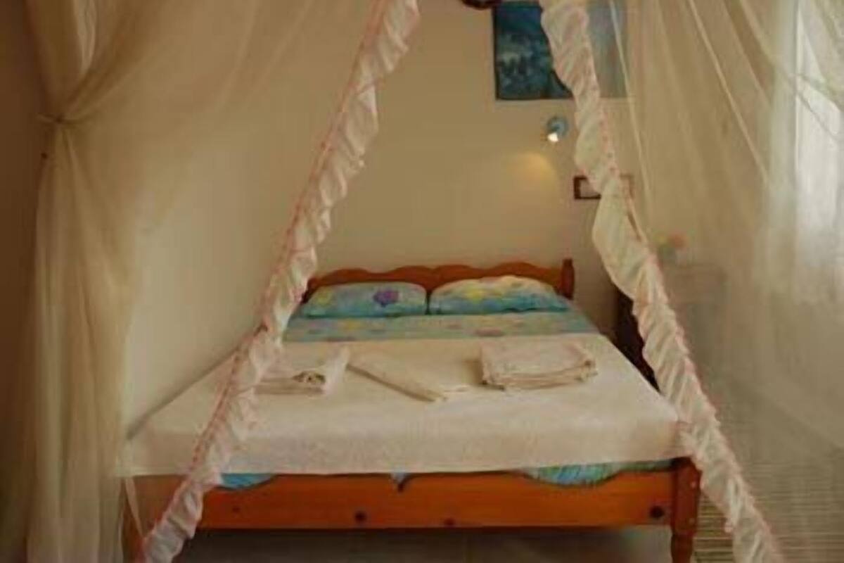 Una cama con dosel, una almohada y una toalla doblada sobre la cama.