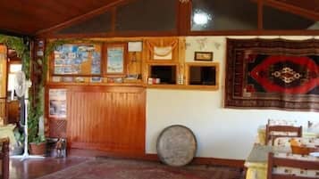 Un interior rústico con paredes de madera, una alfombra grande y un tapiz tradicional en la pared.