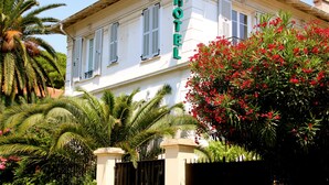 Un edificio blanco con un letrero que dice "HOTEL" en la fachada, rodeado de exuberante vegetación y palmeras.