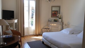 Habitación de hotel con cama, televisor, escritorio con lámpara, una silla y vistas al exterior.