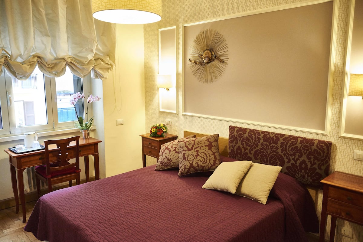 A neatly arranged hotel room with a large bed, a desk, and a chair.