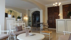 Un ampio soggiorno con mobili bianchi, un tavolo rotondo e un lampadario.