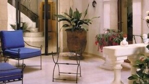 Una hall con una scala, una poltrona blu, una pianta in vaso e una fontana.