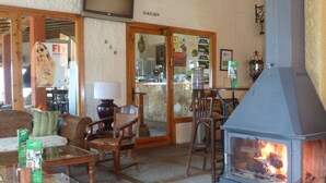 A cozy interior with a wood-burning stove, comfortable seating, and a television mounted on the wall. - Apartamentos San Pedro (La Iruela)