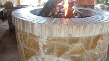 Un hogar de piedra con tapa metálica, rodeado de un patio con suelo de baldosas.
