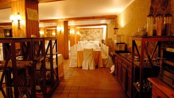 Un restaurante con una larga mesa dispuesta para una comida, muebles de madera y una pared de piedra.