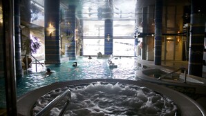 An indoor swimming pool with multiple hot tubs and a view of the outside. - Apartamentos San Pedro (La Iruela)