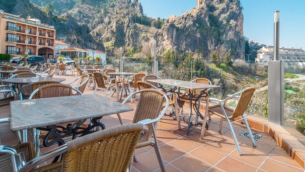 An outdoor terrace with wicker chairs and tables, overlooking a mountainous landscape. - Apartamentos San Pedro (La Iruela)