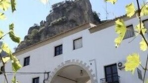 A building with a stone archway entrance, a small staircase leading up to a door, and a balcony with a railing. - Apartamentos San Pedro (La Iruela)