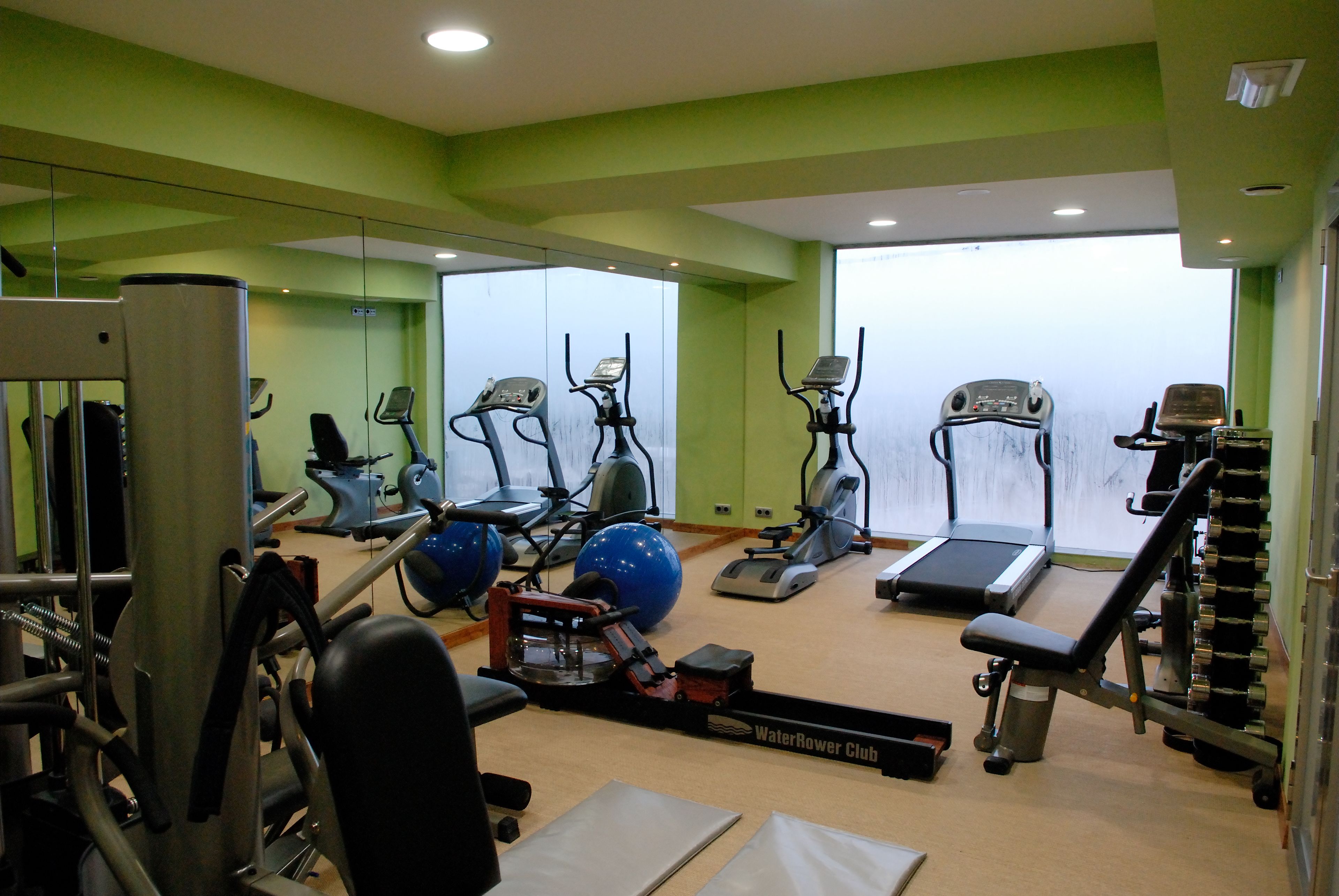 A gym with exercise equipment, a water treadmill, and a mirror wall.