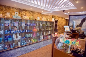 Un vestíbulo de hotel con pared de piedra, una vitrina de vidrio con varios objetos y un techo con tragaluz.