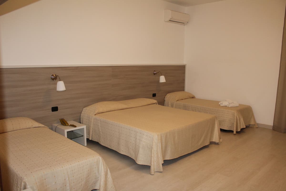A hotel room with two single beds, a nightstand, a lamp, and a small table.