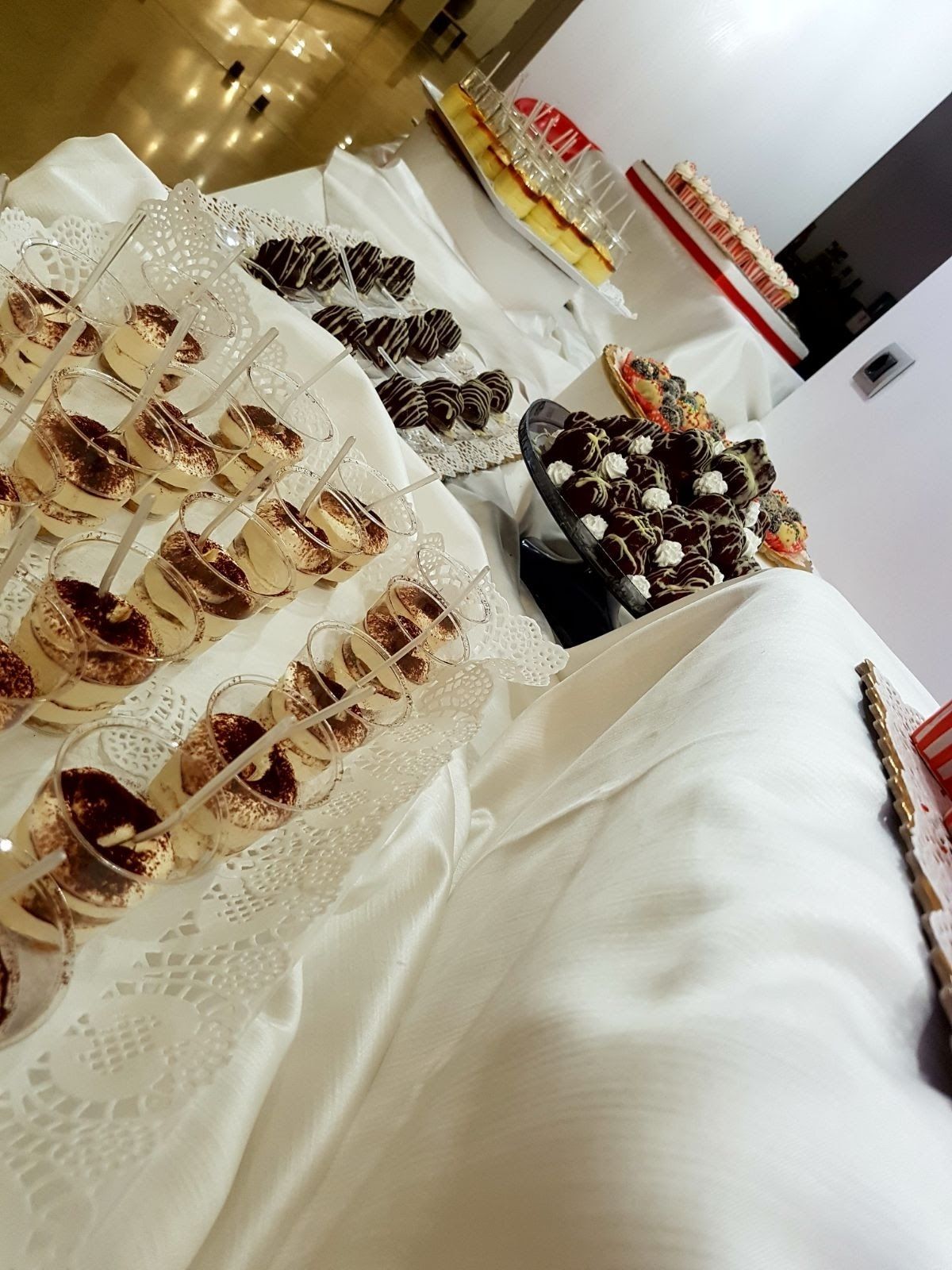 Una mesa con diversos postres y un mantel de encaje blanco.
