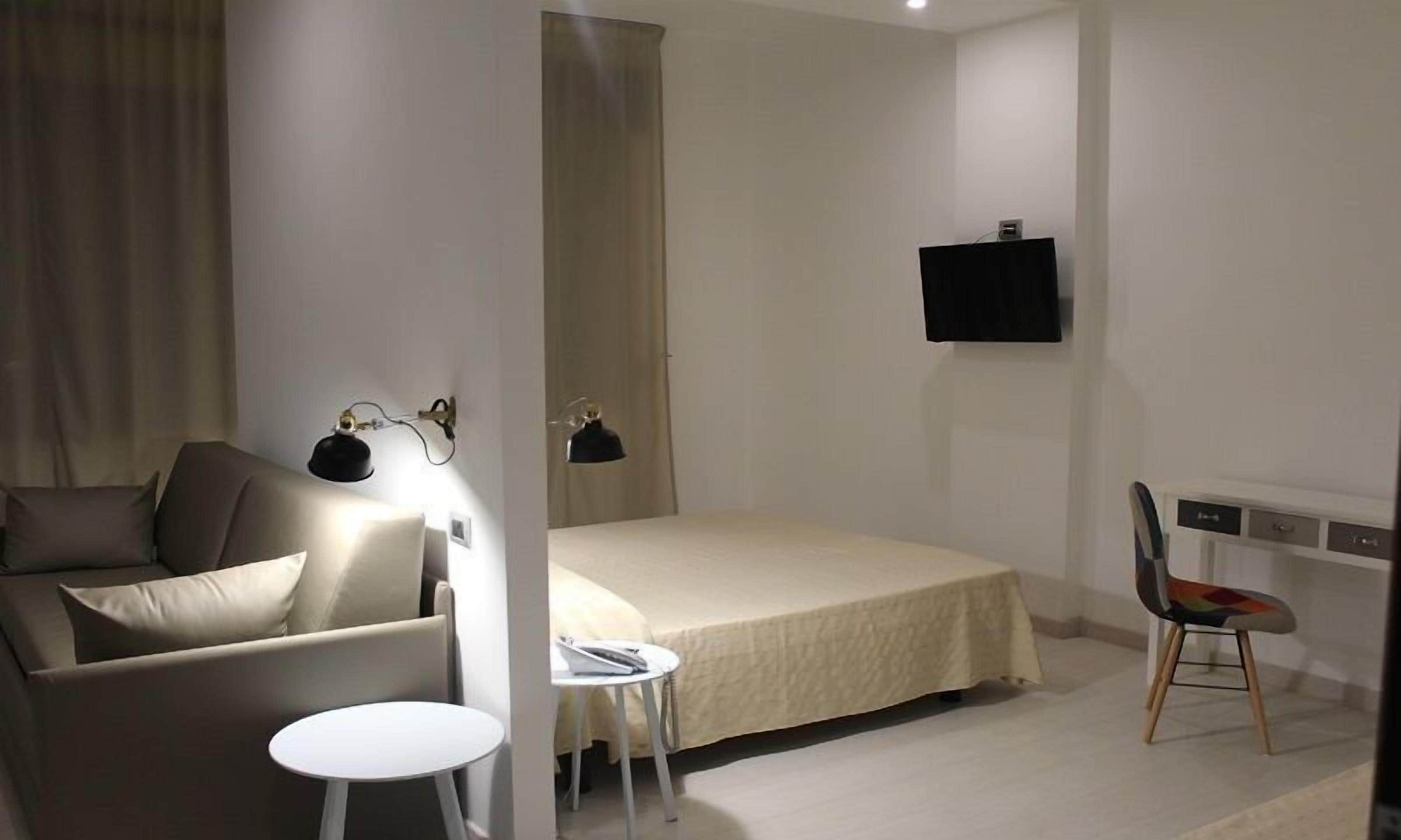 Un dormitorio con cama, una silla, un escritorio y un televisor.