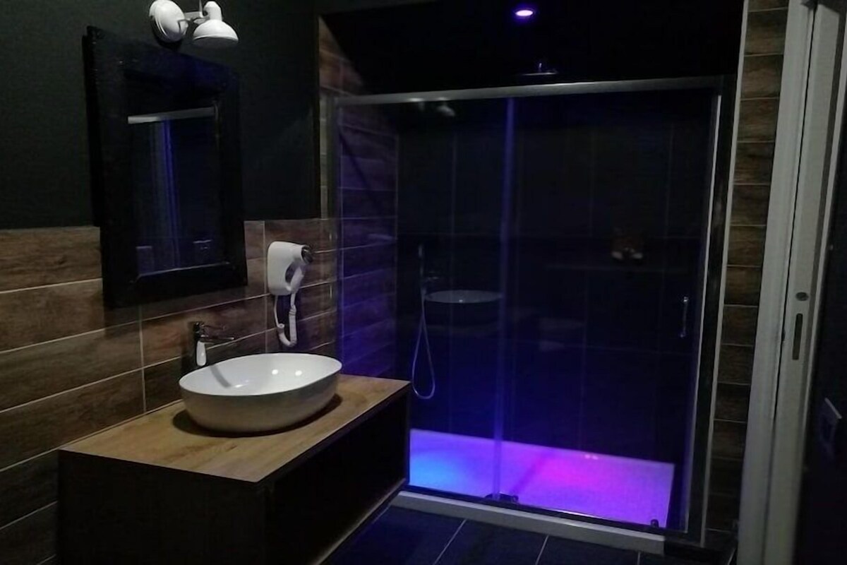 A modern bathroom with a large sink, a mirror, and a glass-enclosed shower.