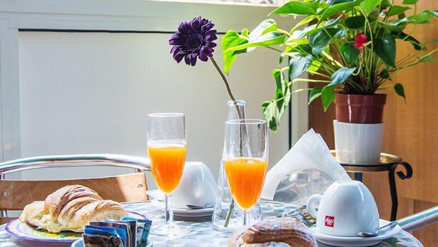 Mesa de café da manhã com croissants, copos de suco e xícara de café.