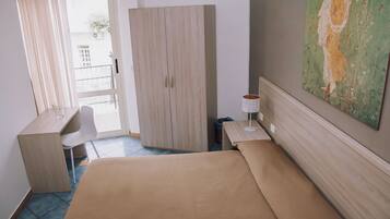 Ein Hotelzimmer mit Bett, Schreibtisch, Stuhl, Lampe und einem Bild an der Wand.