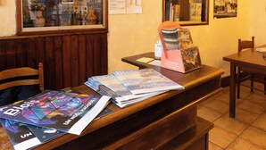 A reception desk with magazines, a bottle of water, and a framed picture on the wall. - Hôtel du Bellay (Blois)