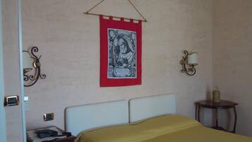 A bedroom with a bed, a bedside table, a lamp, and a wall hanging.