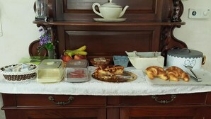 Un bufé de desayuno con diversas opciones de comida, una tetera y un reloj en la pared.