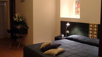 A bedroom with a bed, a desk, a chair, a lamp, and a mirror.