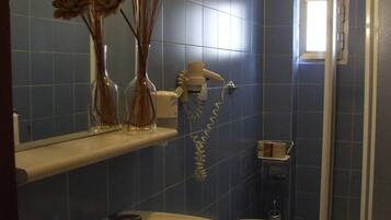 Een badkamer met een grote wastafel, toilet en douchegedeelte. Op de wastafel staan decoratieve vazen en boven het toilet een handdoekhouder.