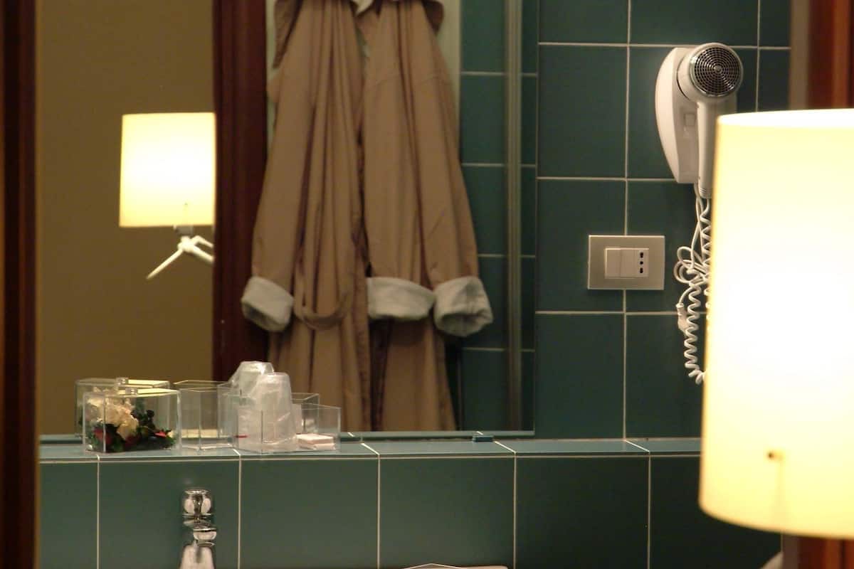 A bathroom with a sink, mirror, towel rack, and a hairdryer.