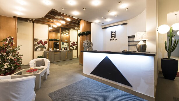 A hotel reception area with a modern design, featuring a reception desk, seating area, and a Christmas tree. - Hotel Orvieto (Orvieto)
