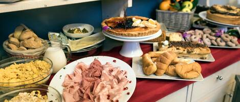 Una mesa de buffet con diversos alimentos, como pasteles, carnes y postres.