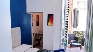 Quarto com cama, cadeira, mesa e vista para o exterior.