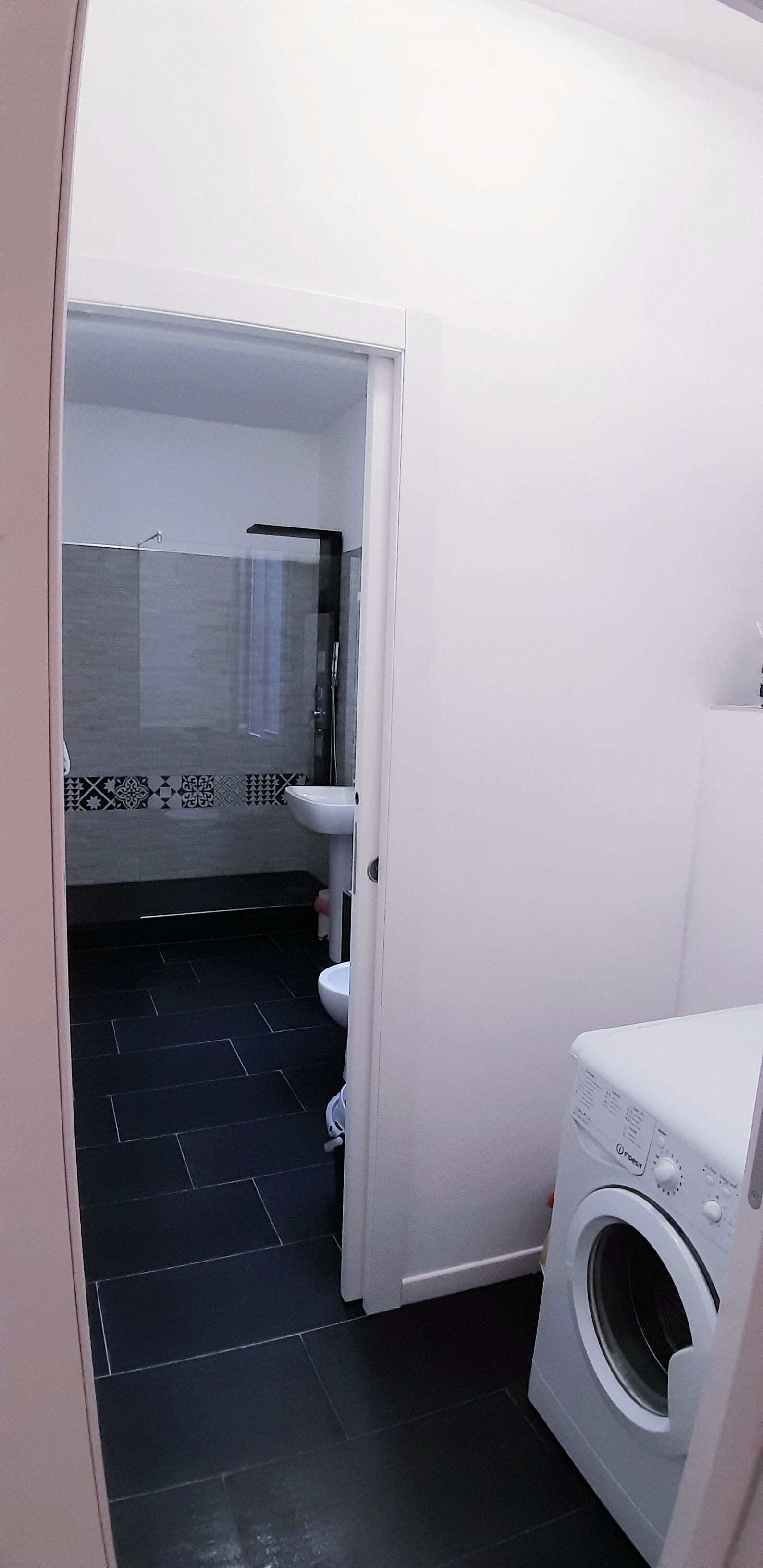 Un baño pequeño con lavadora, inodoro y zona de ducha.